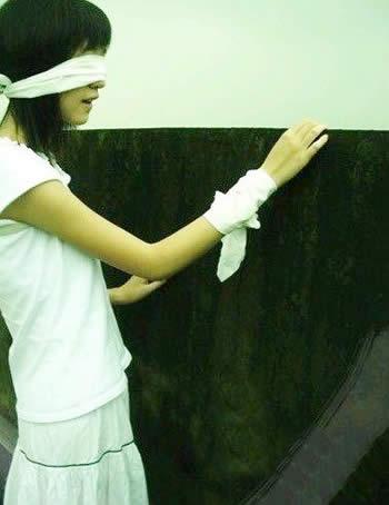 双眼遮住的伤感女孩摸着墙在走