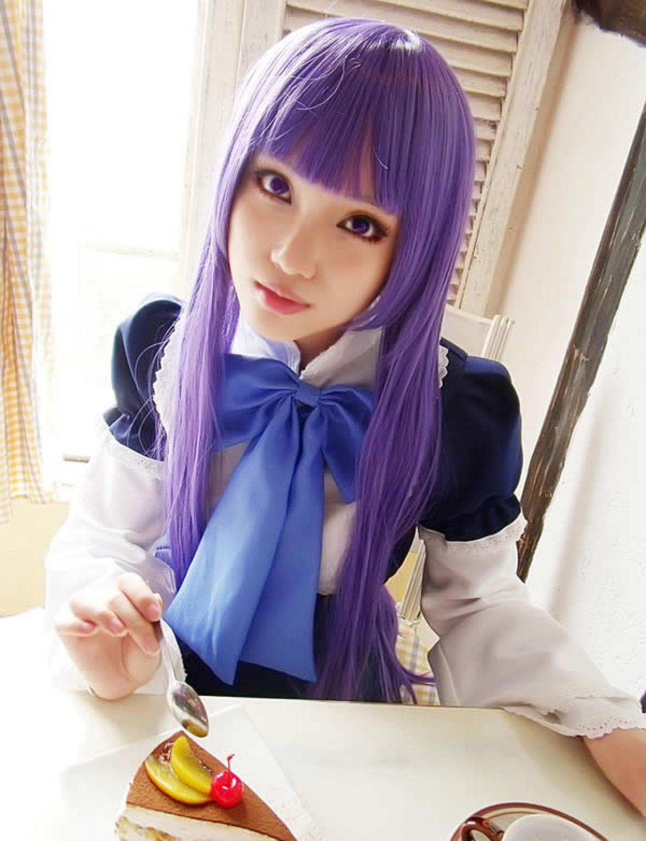 猫嫌身着紫色服饰手持勺子吃小甜点的照片