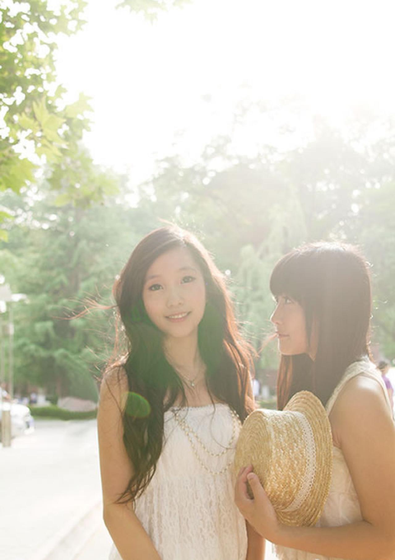 蕊蕊Thea姊妹写真集姐姐对着镜头微笑，妹妹拿着草帽看着姐姐