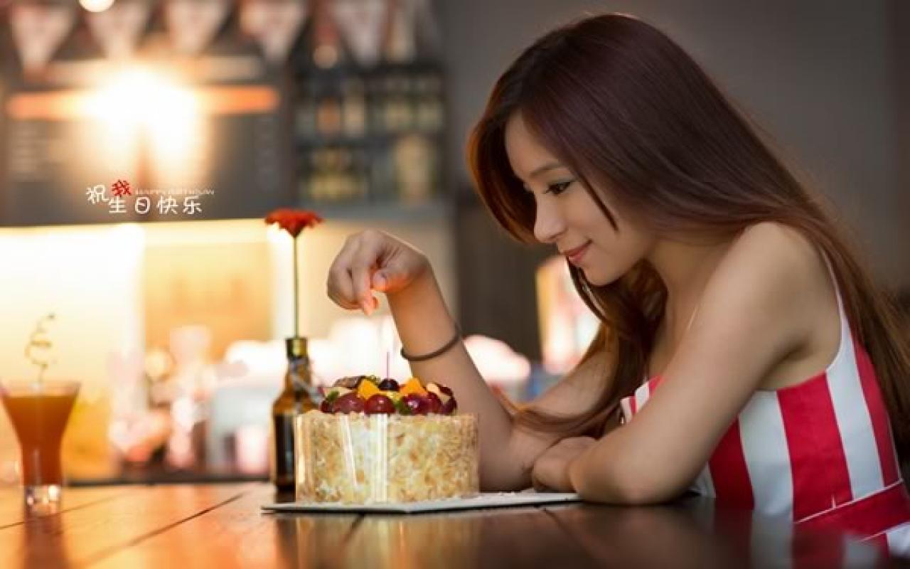 几位穿红色条纹衣裤的姑娘在酒吧生日聚会，过生日的姑娘独自一人面对着点着一只蜡烛的小蛋糕