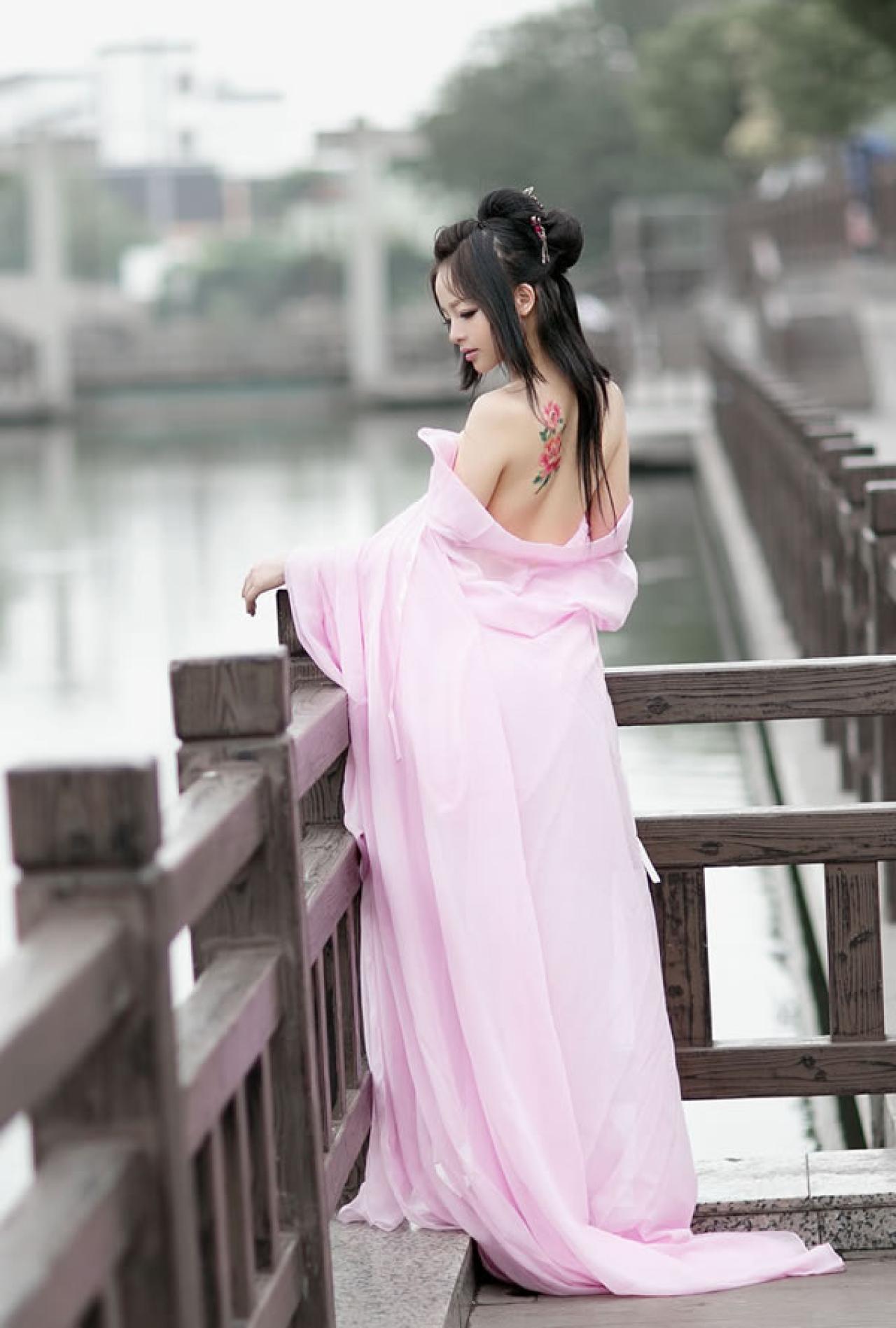歪歪穿着粉色绸缎扶着木栏杆看着自己的手
