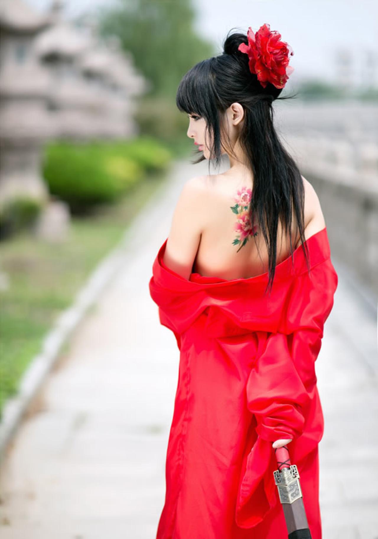 歪歪穿着大红色绸缎手里扶着剑背影全身照