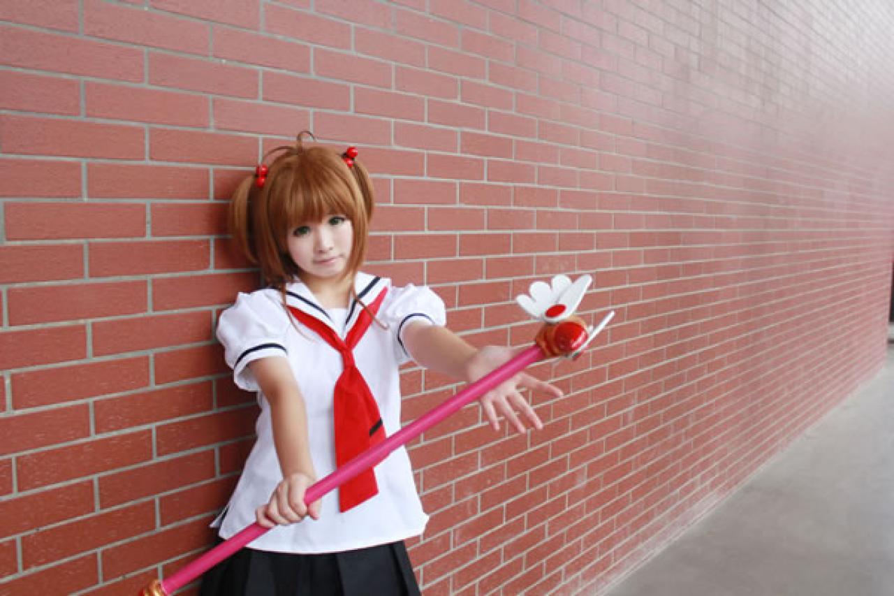 米兔扮演魔法少女穿着校服靠在红砖墙上，双手平举起魔法杖