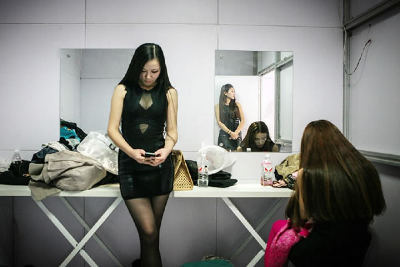 90后Showgirl王可欣在展台后台查看手机