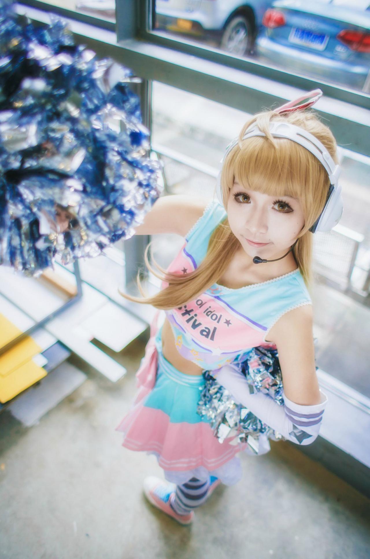 手上拿着花球，戴着耳机，像是扮演偶像大师里的角色