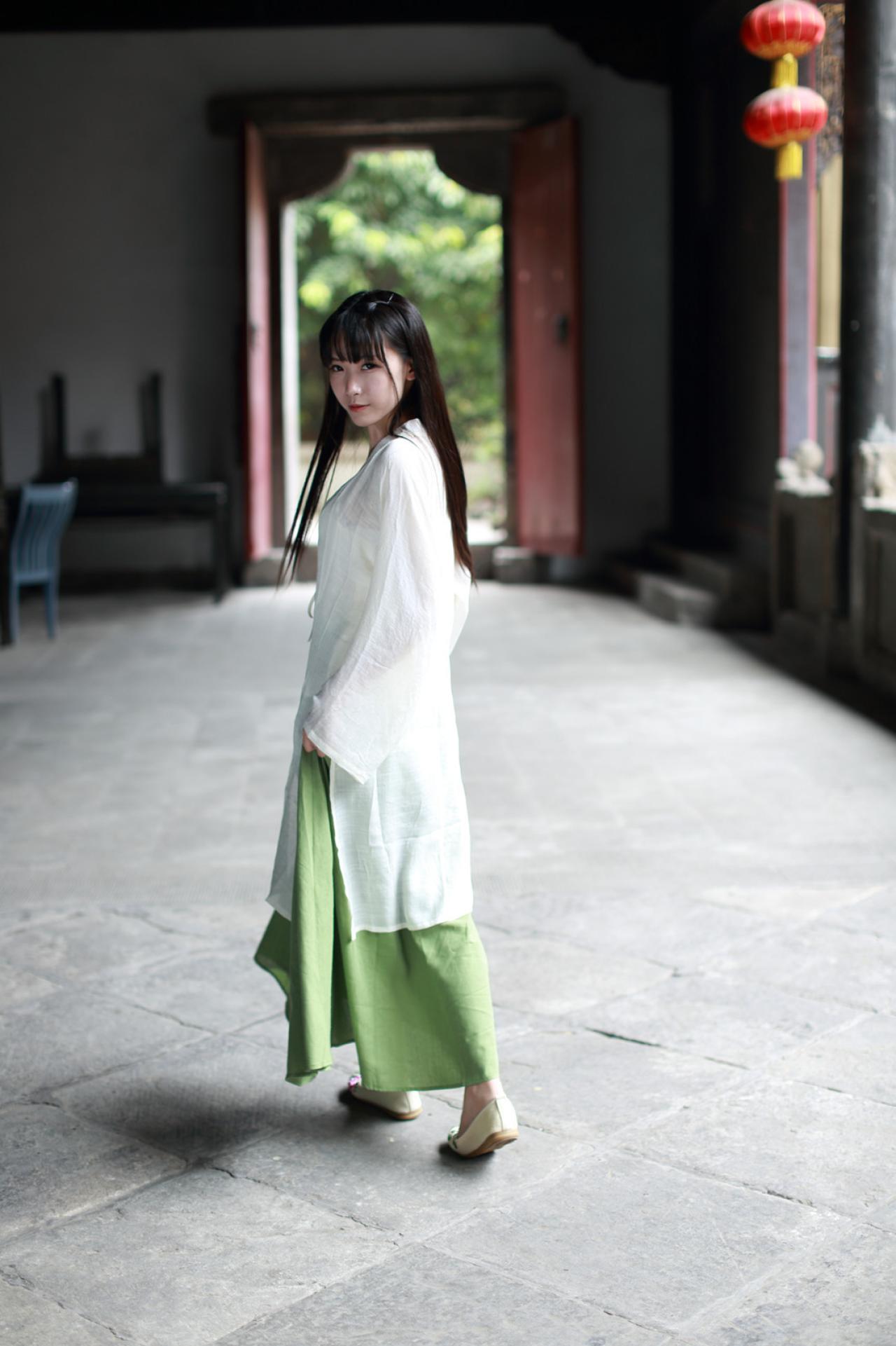 半藏森林穿着白色对襟褙子长款上衣走在石路上侧身回头看的样子