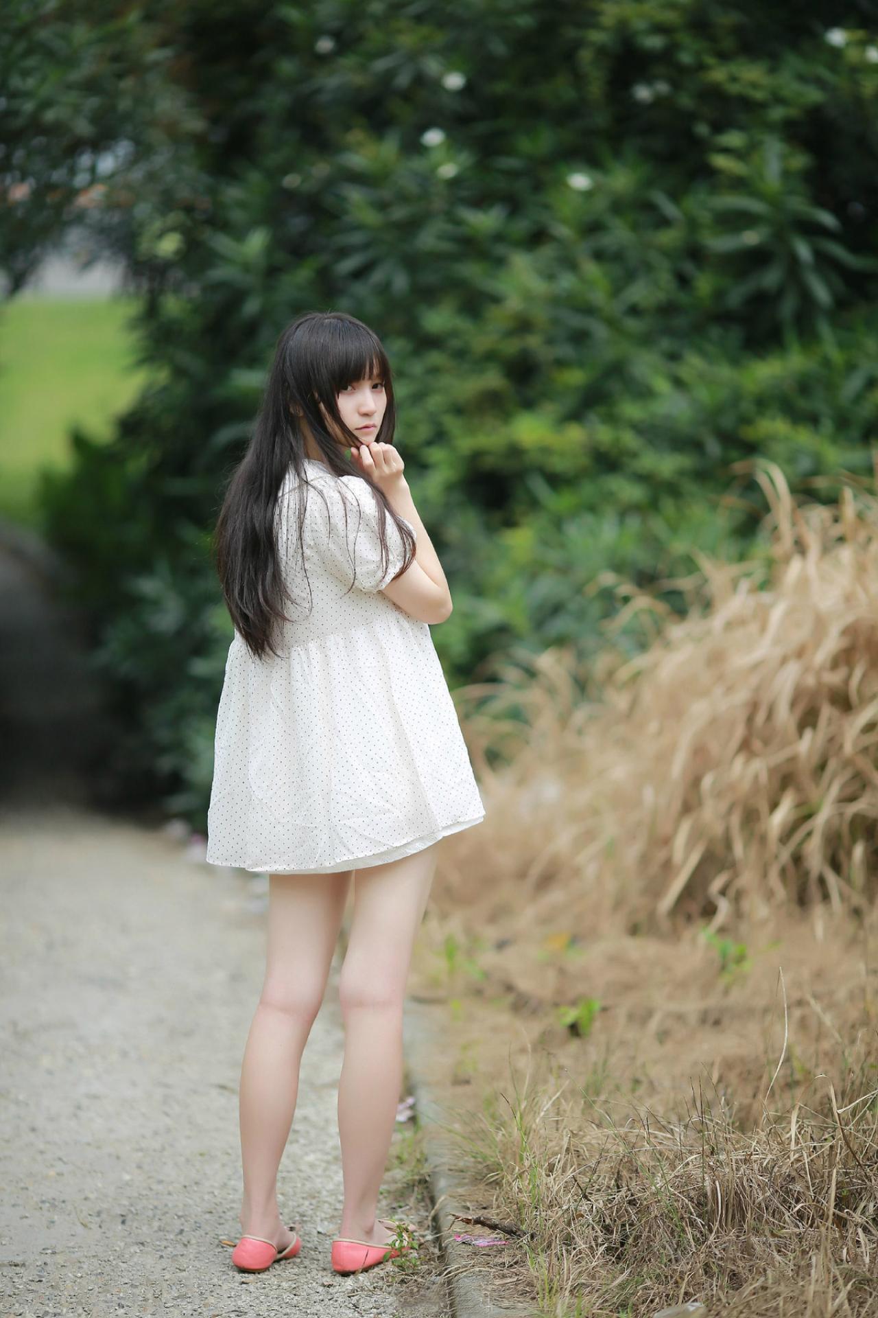 苏里柟穿着白色波点罩衫走在路上回眸思考的姿势