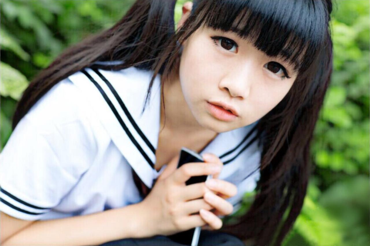 草纸双手握着手机在绿叶中蹲下时的脸部特写