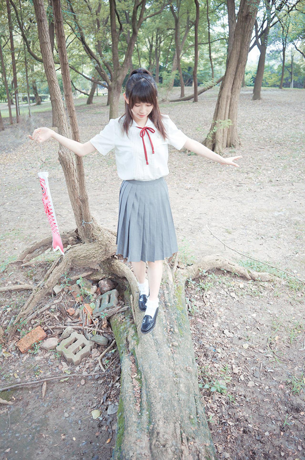 许夏幽拎着一只红色鲤鱼旗走在树干上，双手伸展保持平衡