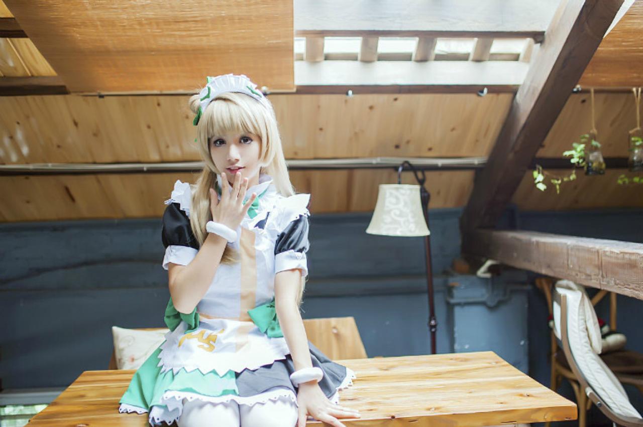 冰夜酱扮演南小鸟右手五指伸开放在嘴边，掩嘴微笑着坐在桌子上