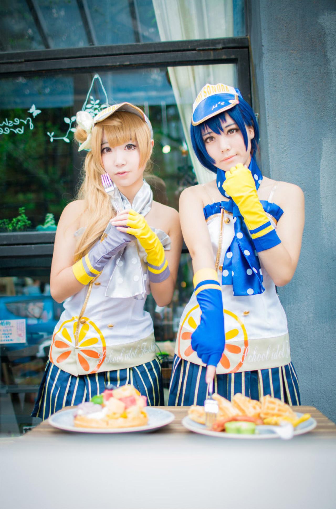 木年年扮演园田海未捻着下巴，黑川扮演南小鸟拿着叉子，面前是两盘食物