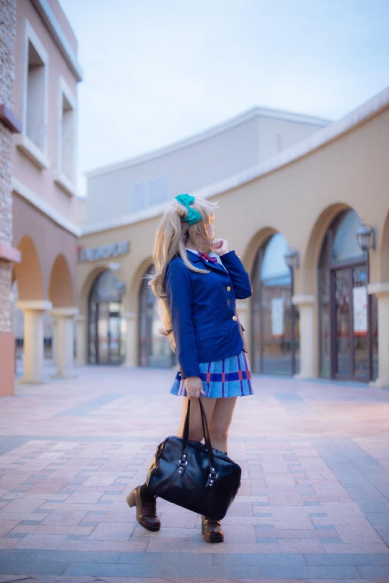 四月www扮演南小鸟右手提着挂包，左手扶着下巴回头看的姿势