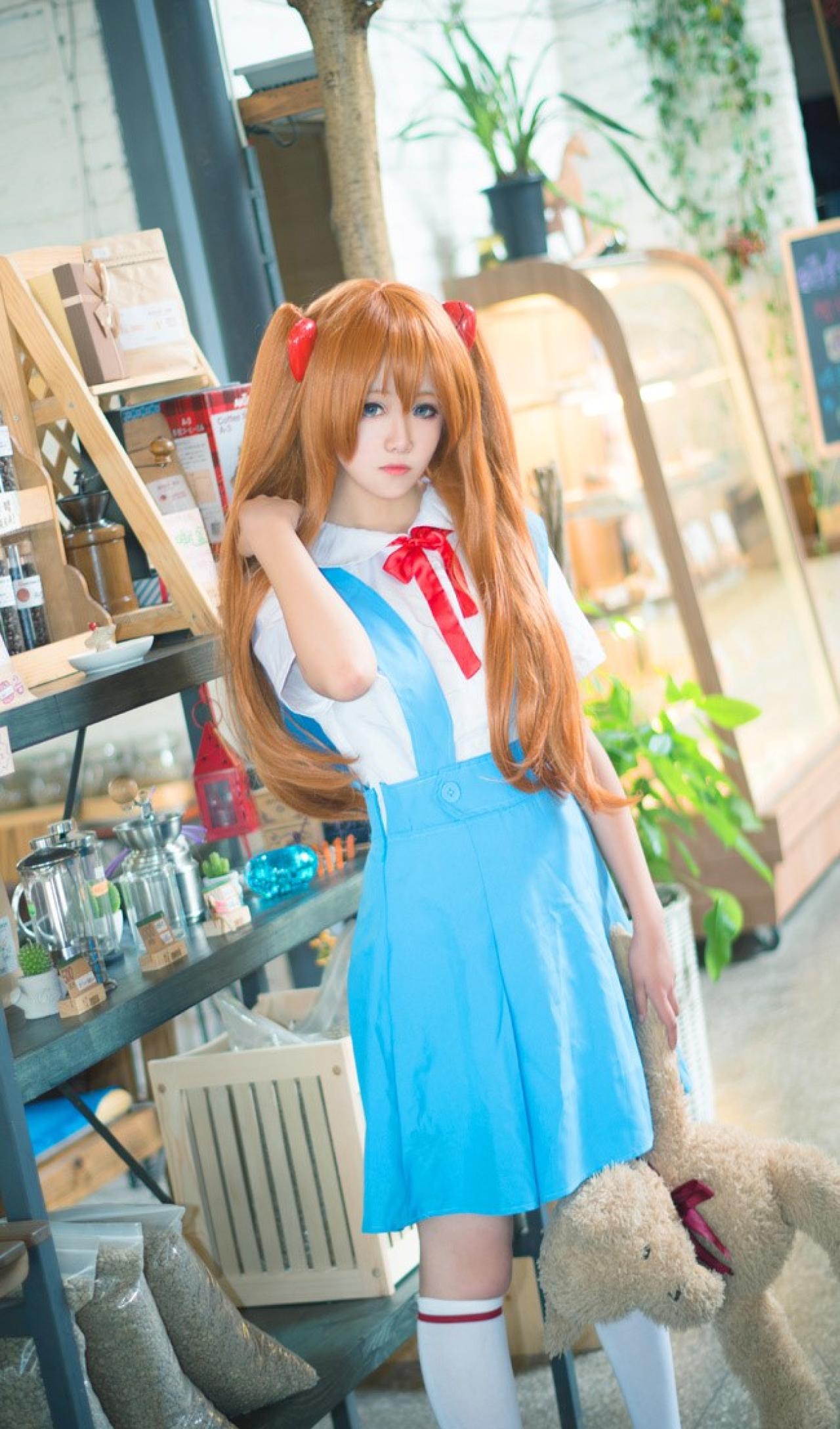 侒君扮演明日香右手轻捋马尾，左手拎着一只毛绒玩具的胳臂