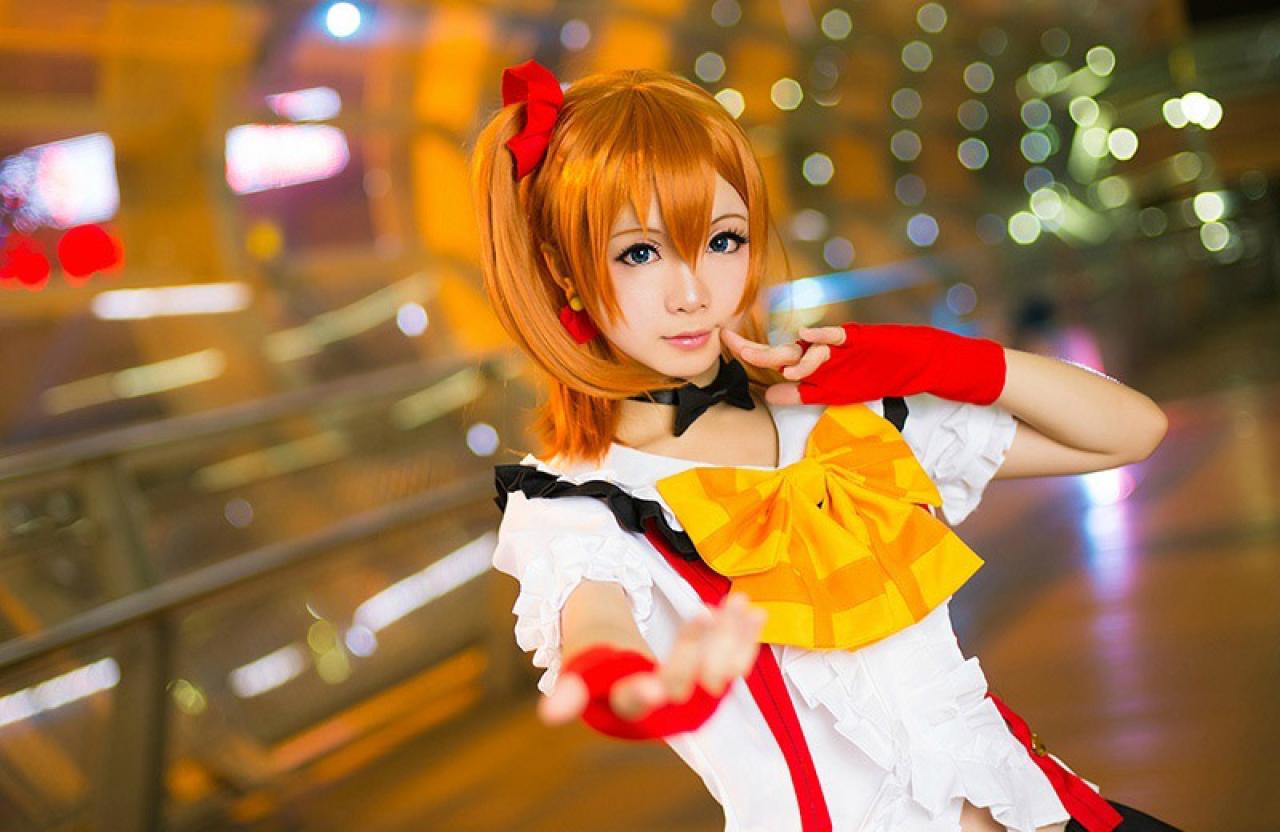 Hoshilily扮演高坂穗乃果左手扶着嘴角，右手伸向镜头的姿势