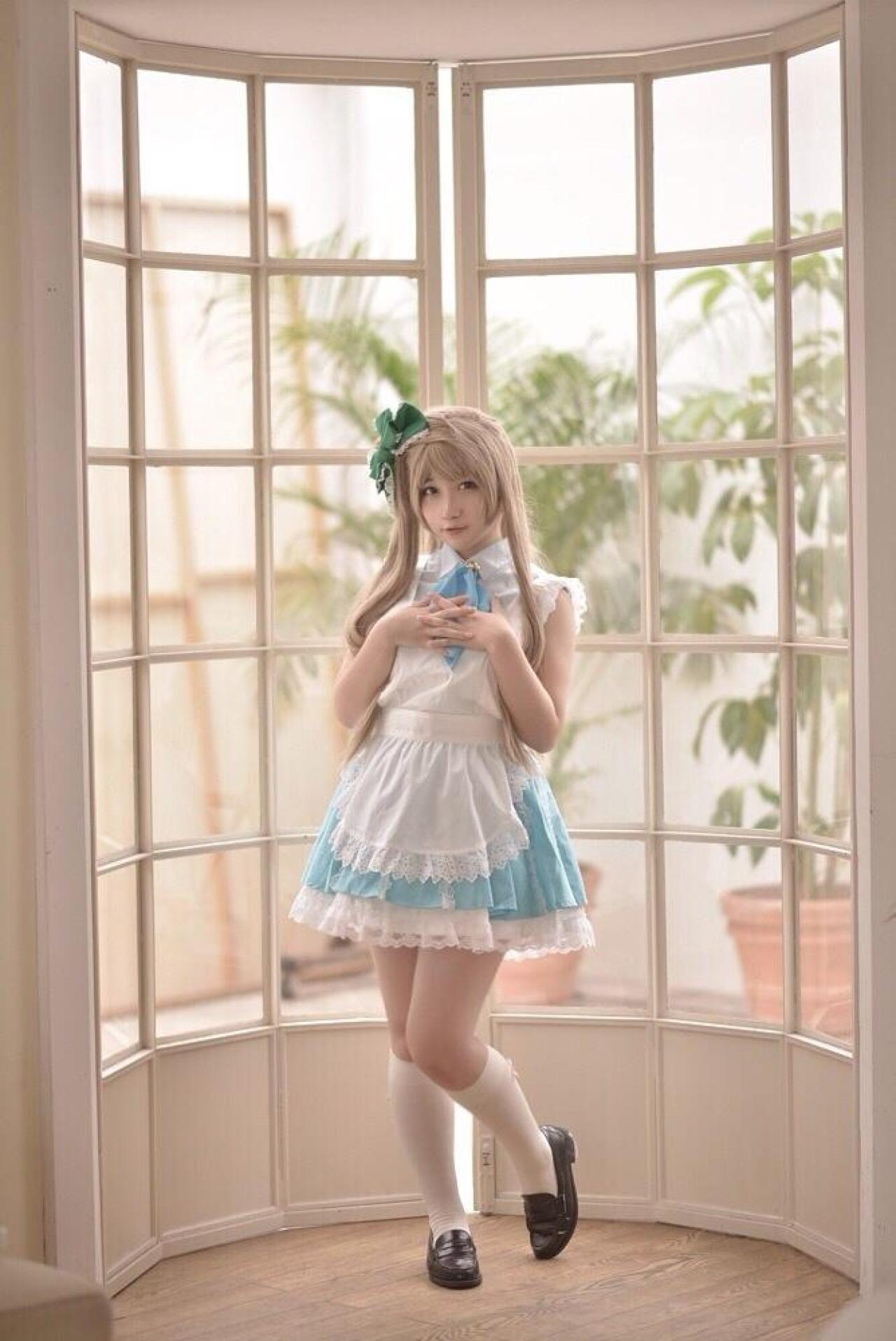 橘猫汰扮演南小鸟双手叠放在胸前，在落地窗里站立的全身照