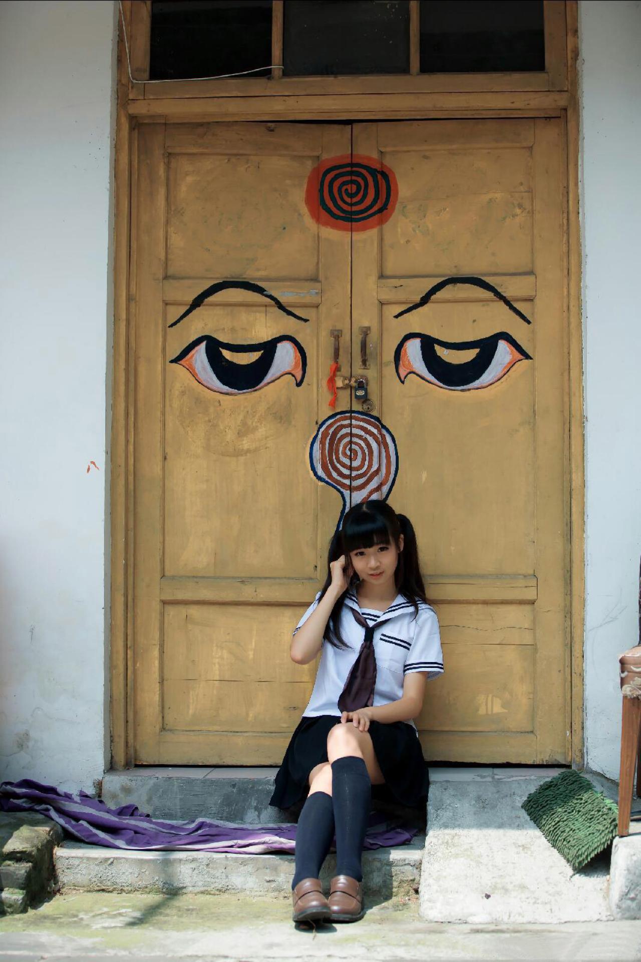 机智草纸坐在黄色油漆涂抹过双开门前的石阶上，捋头发的样子