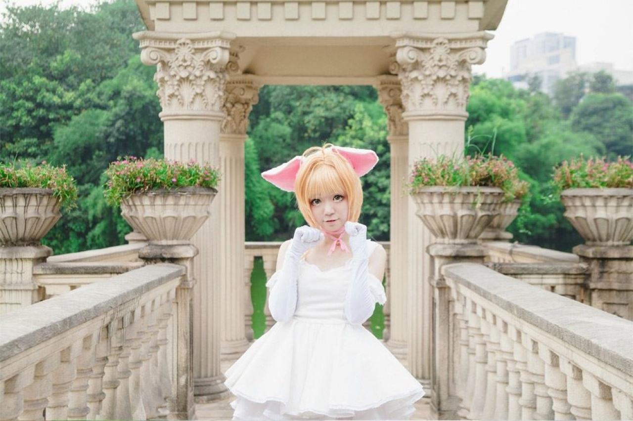 阿八扮演木之本樱双手放在胸前，在门前扮小猫姿势