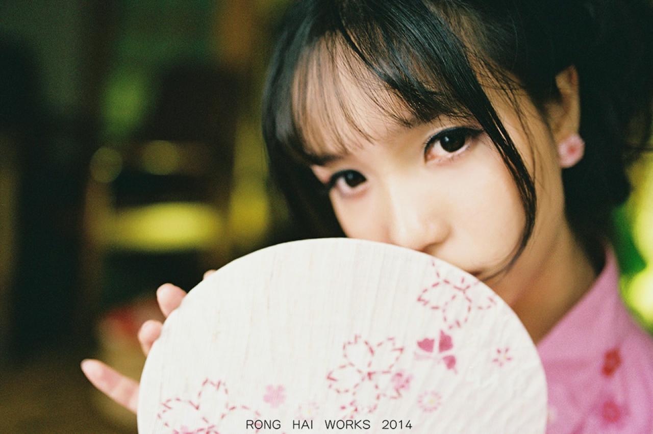 七七把脸藏在扇子后面