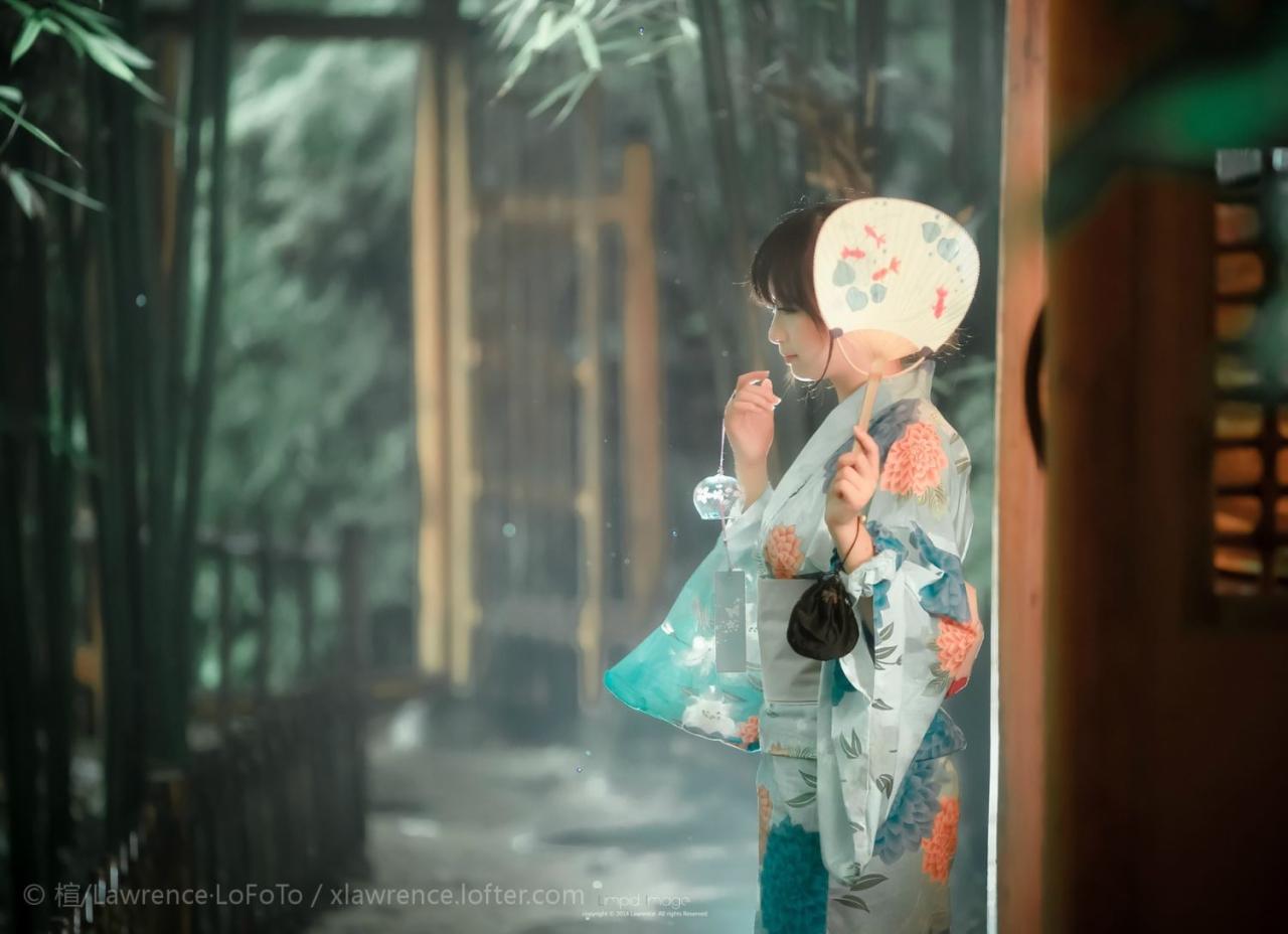 蓝色和服少女拿着右手拿着风铃，左手拿着扇子侧面照