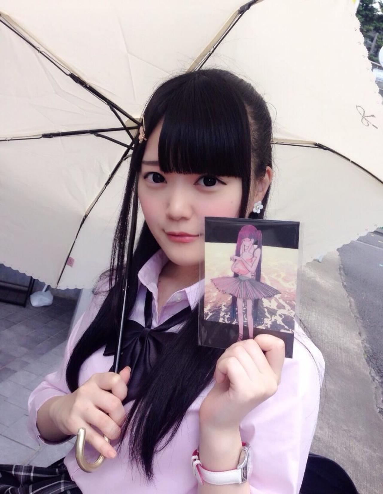 まきろん撑着伞手里拿着明信片