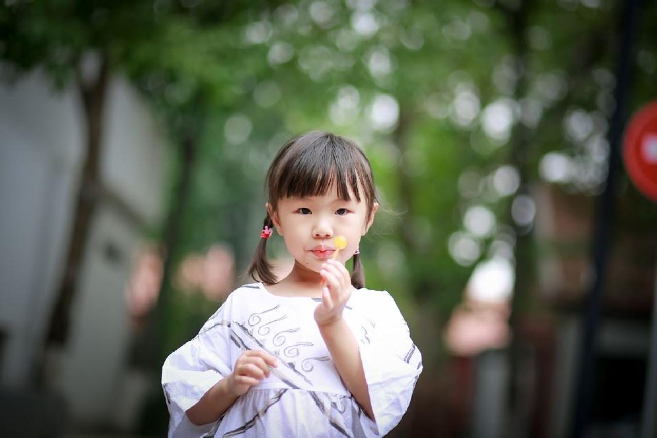 小女孩吹一吹棒棒糖的样子