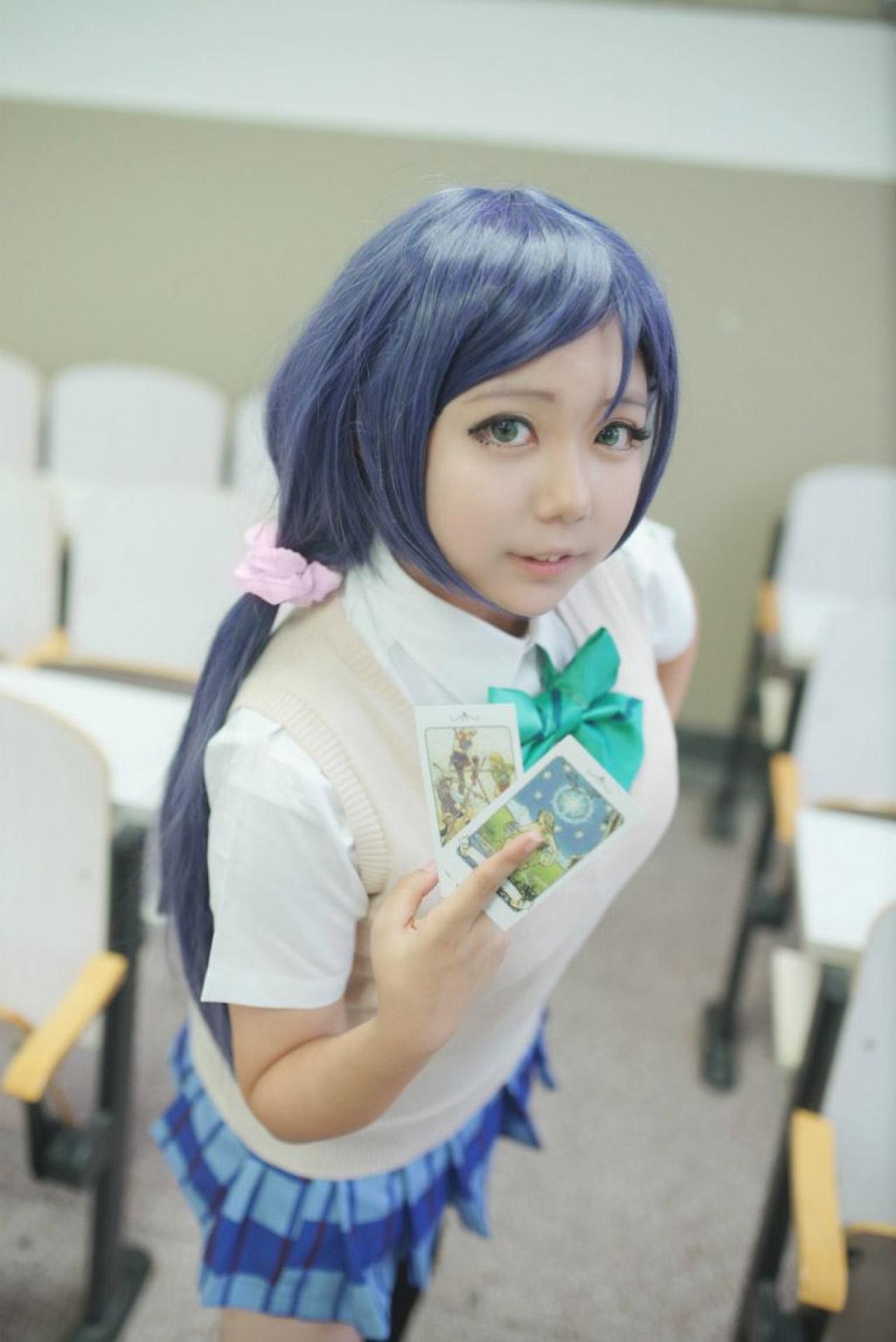 慕斯扮演东条希左手叉腰，右手捏着两张塔罗牌