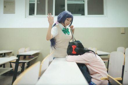 慕斯扮演东条希扬起右手准备拍扒桌上的阿琴扮演的矢泽妮可