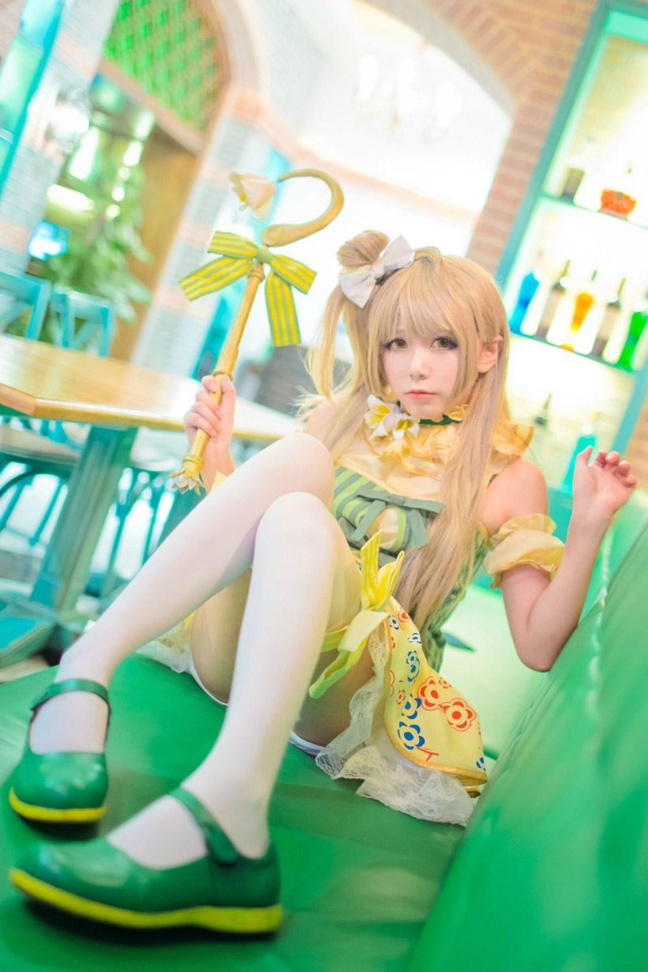 胡纸姐姐扮演南小鸟侧身坐在椅子上，右手拿着风铃花手杖