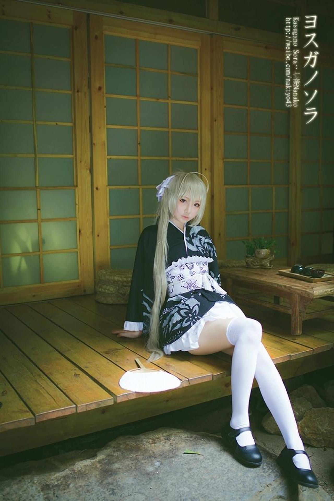 七奈扮演春日野穹坐在门前，上身后仰，双手撑在木板上，身旁放着扇子