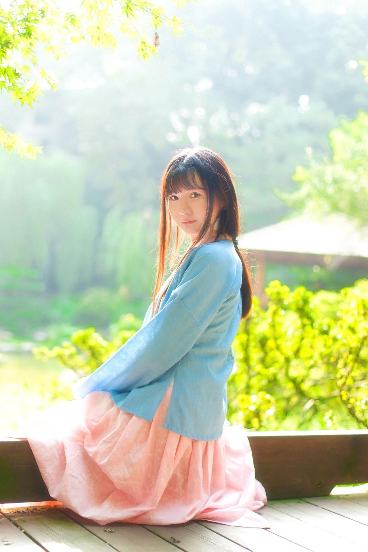 瞬瞬穿着蓝色上衫，粉色长裙坐在门槛上