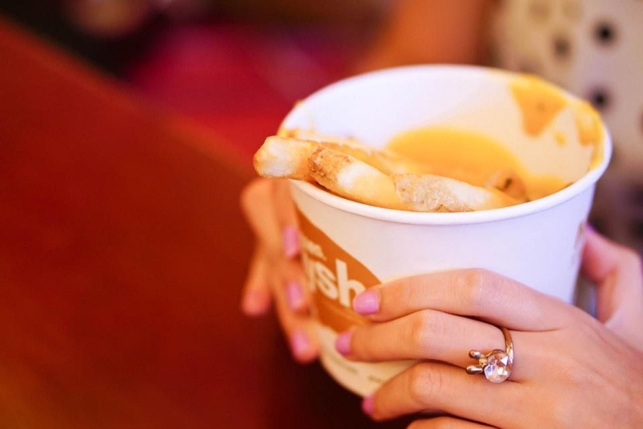 双手捧着的盛薯条的纸杯