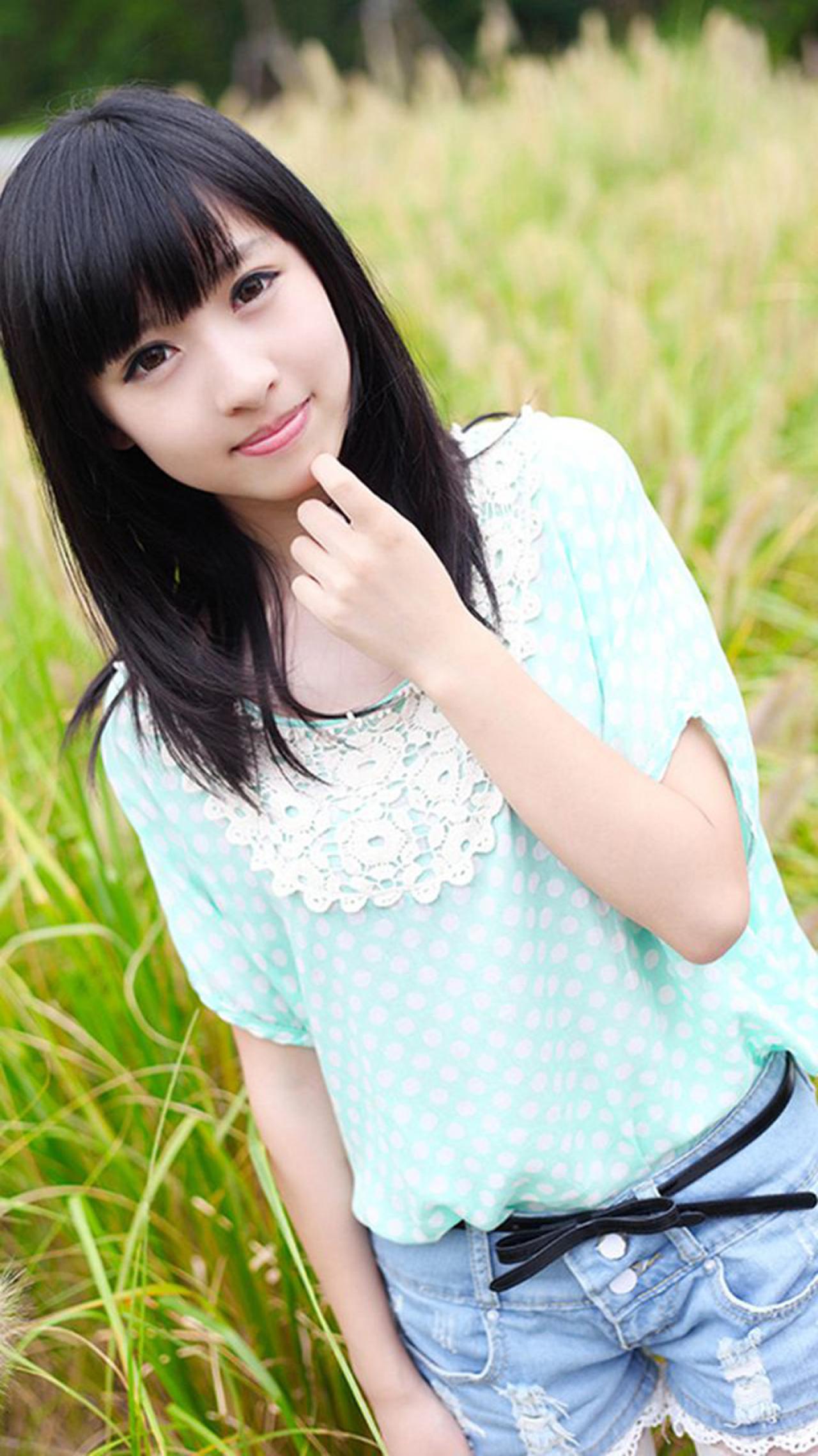 彤彤左手食指贴着下巴，在芦苇丛中