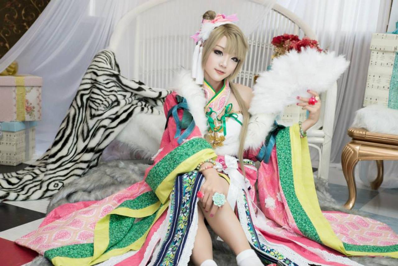 Miyuko扮演南小鸟左手持扇，右手搭在膝盖上