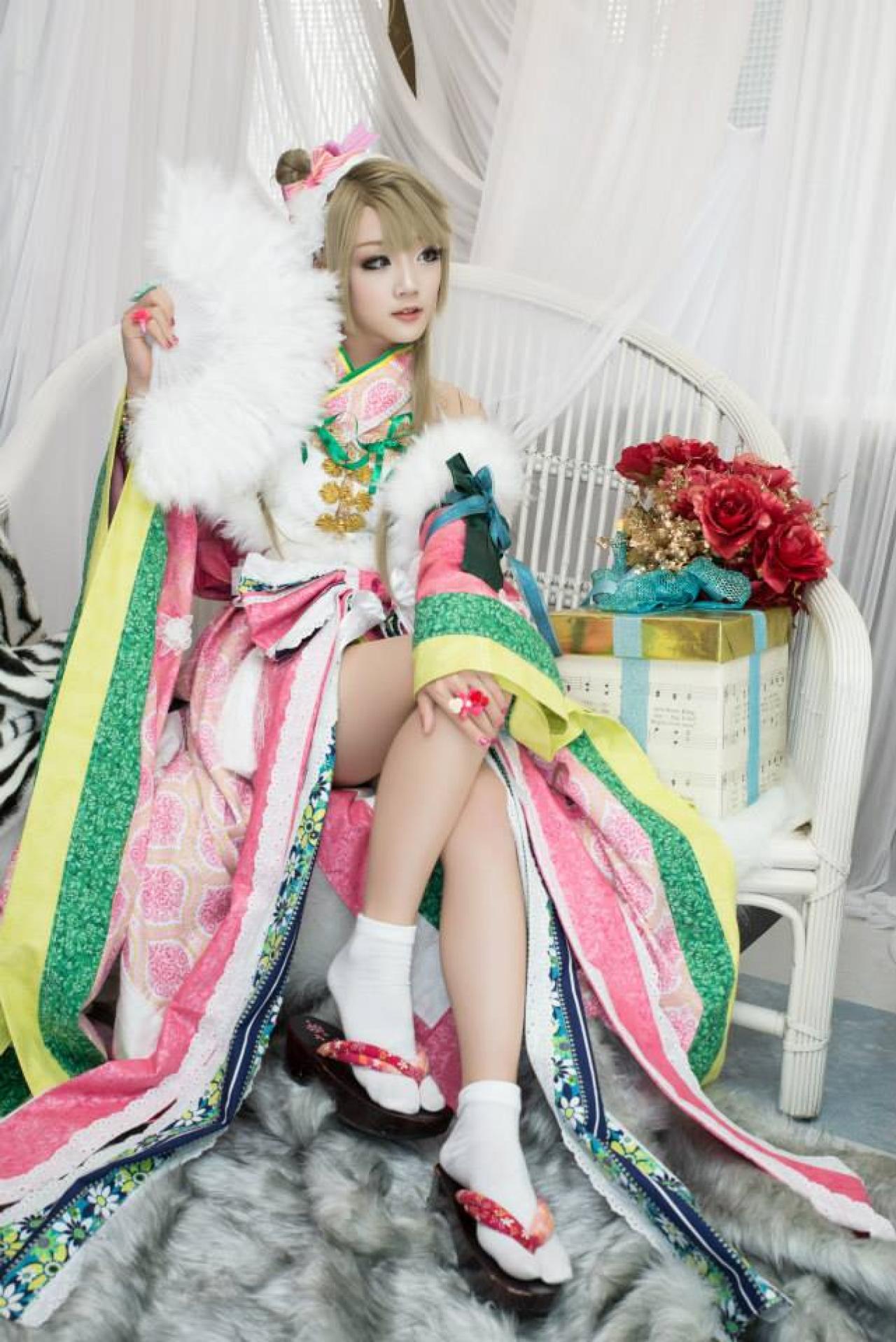 Miyuko扮演南小鸟右手持扇，左手搭在膝盖上