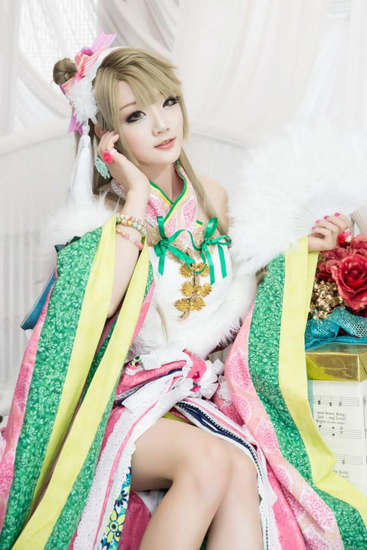 Miyuko扮演南小鸟左手持扇，右手轻抚刘海儿，坐在椅子上