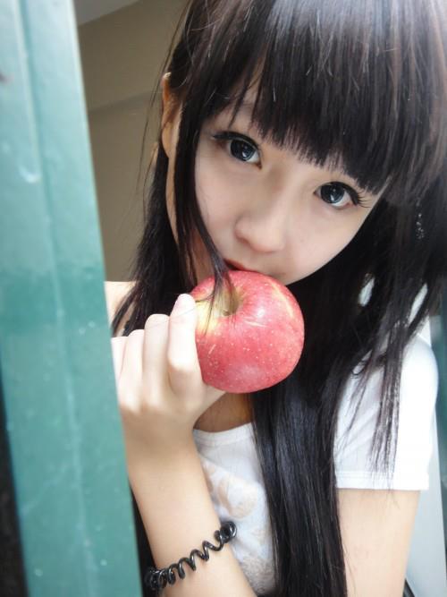 韩晓嗳穿着白色上衣躲在门后咬着苹果：你是谁？