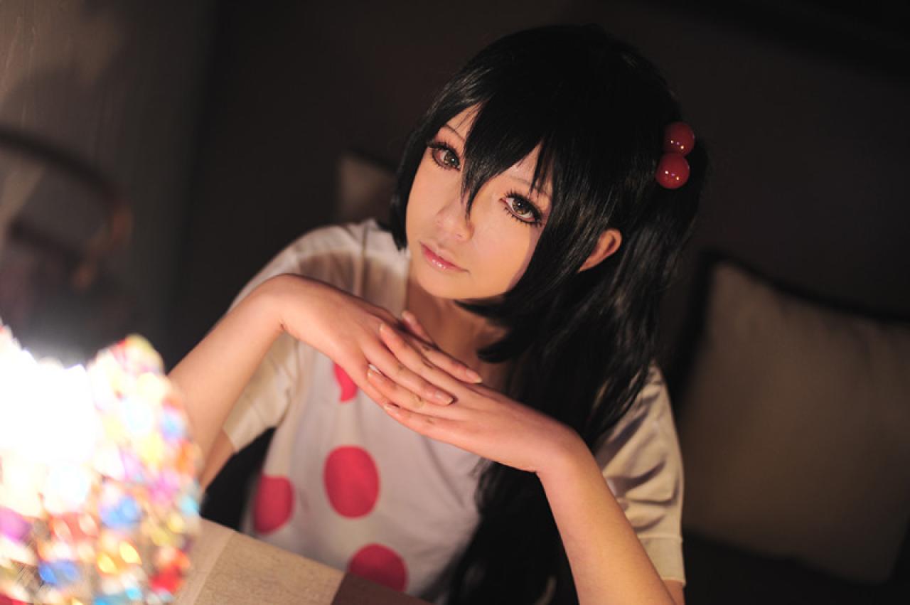 千叶泠扮演中野梓坐在桌旁，双手五指交叉撑在桌面