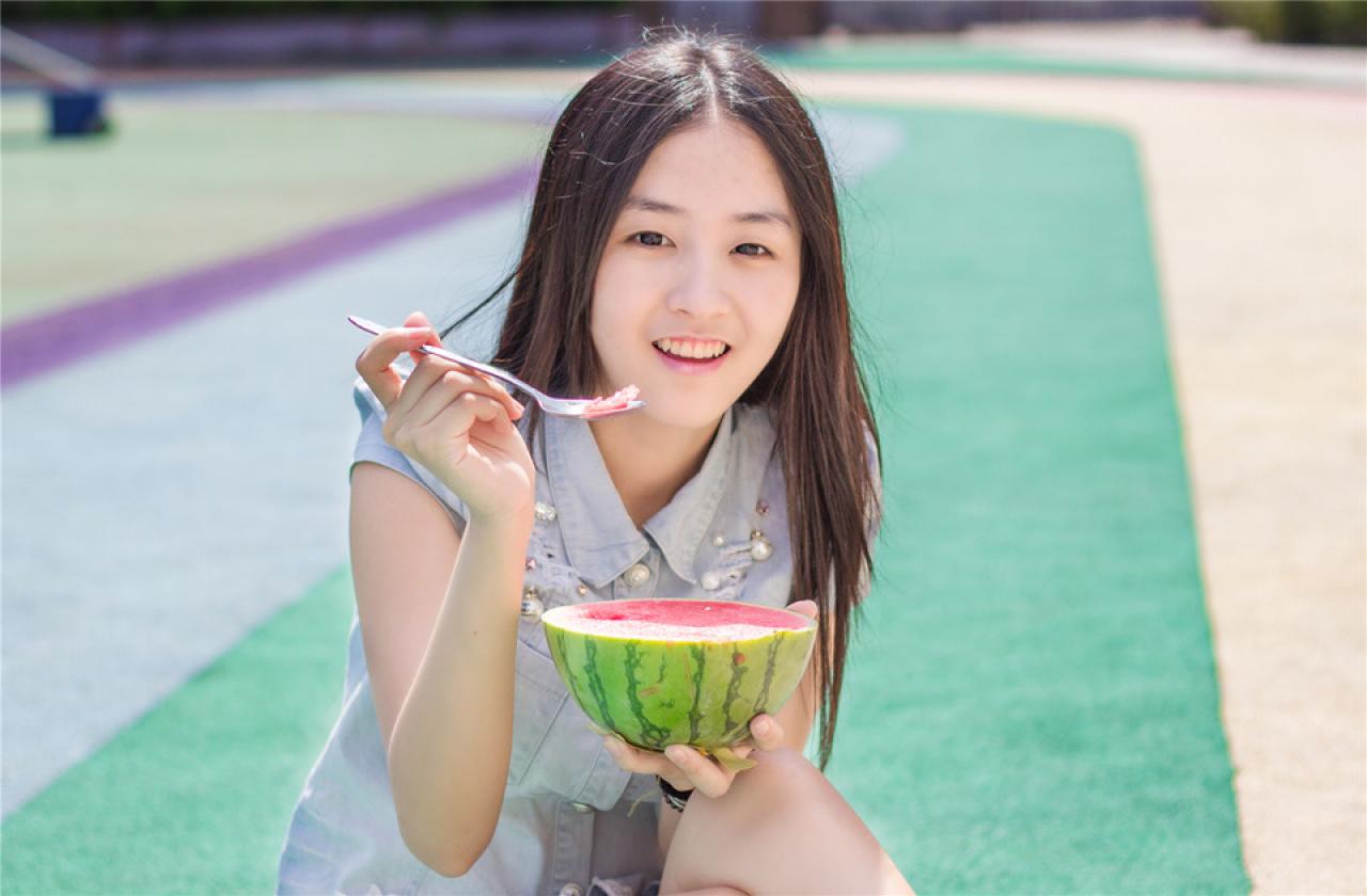 陈婕左手端着西瓜，右手拿着勺子，微笑的神情