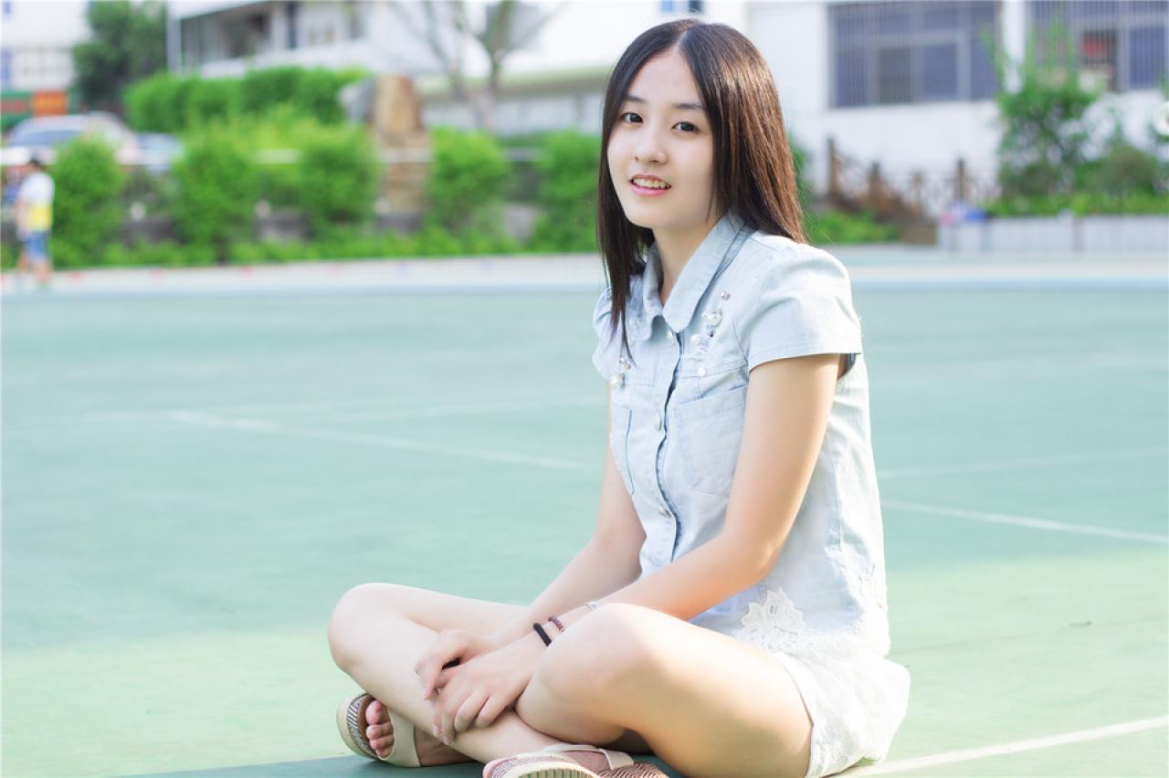 陈婕盘腿坐在球场上，侧面照
