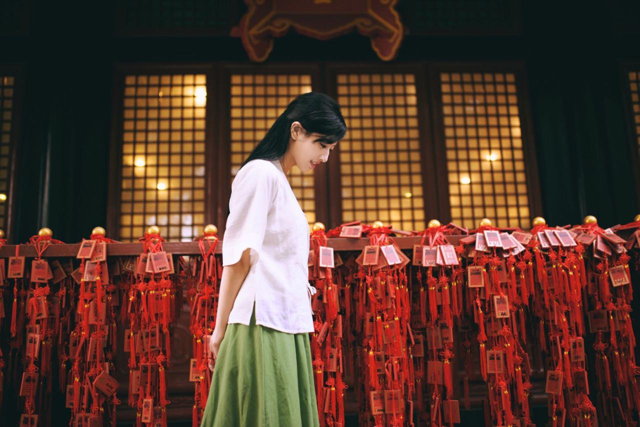 语希范双手背后，从一排排中国结走过，侧面