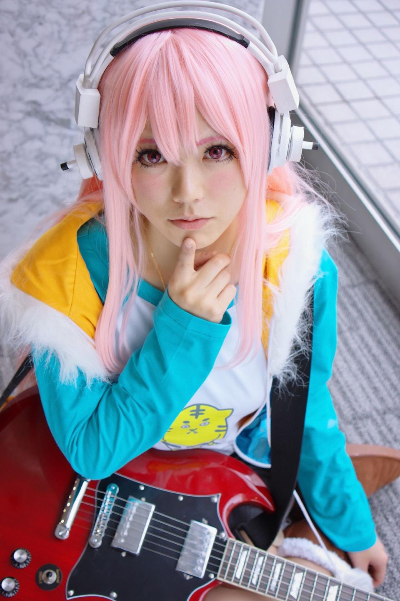 春宮ゆん扮超级索尼子戴着吉他，食指贴在下巴，仰望镜头