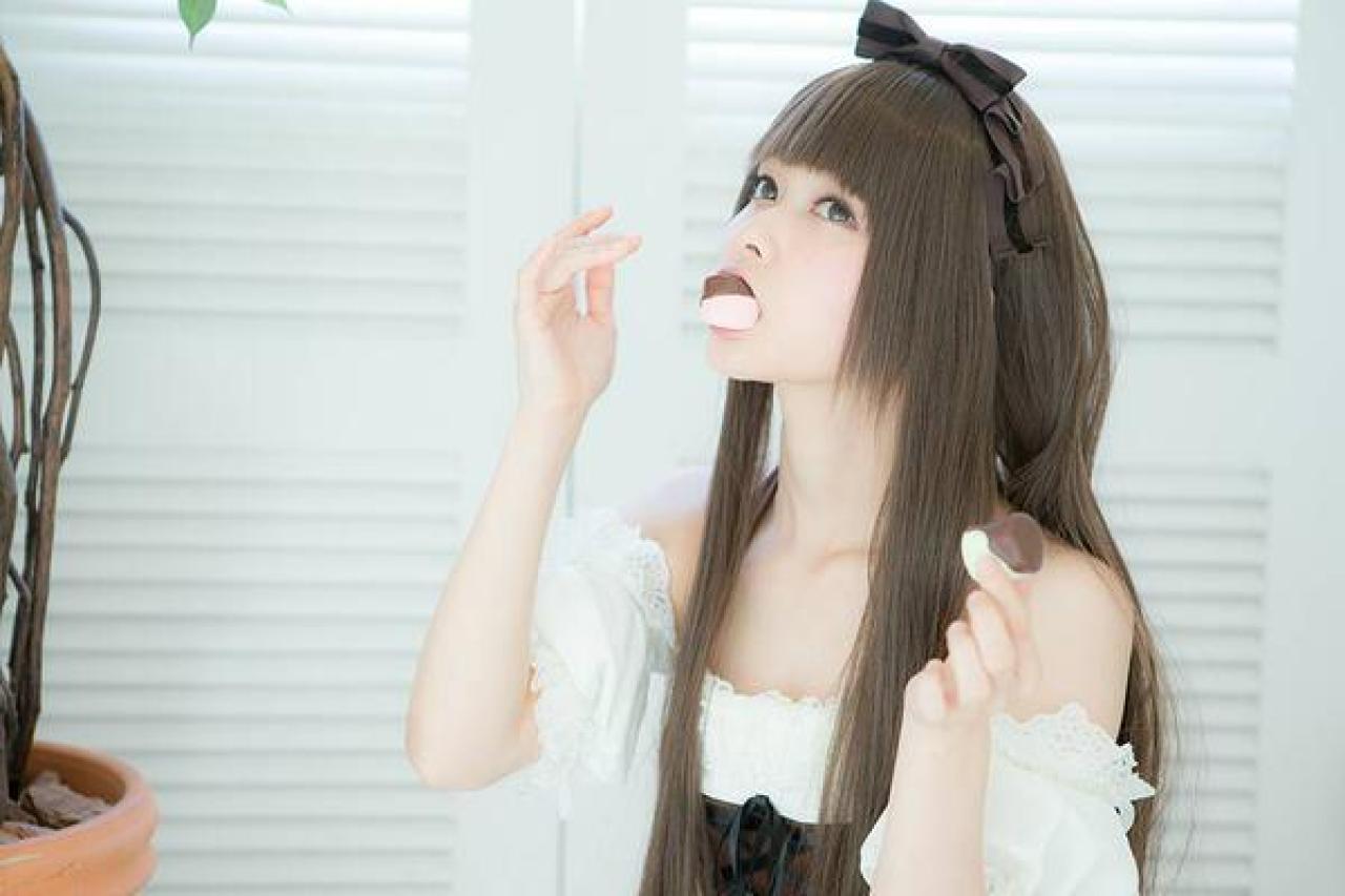 とめと左手端着盘子，嘴里咬着一枚巧克力蛋糕