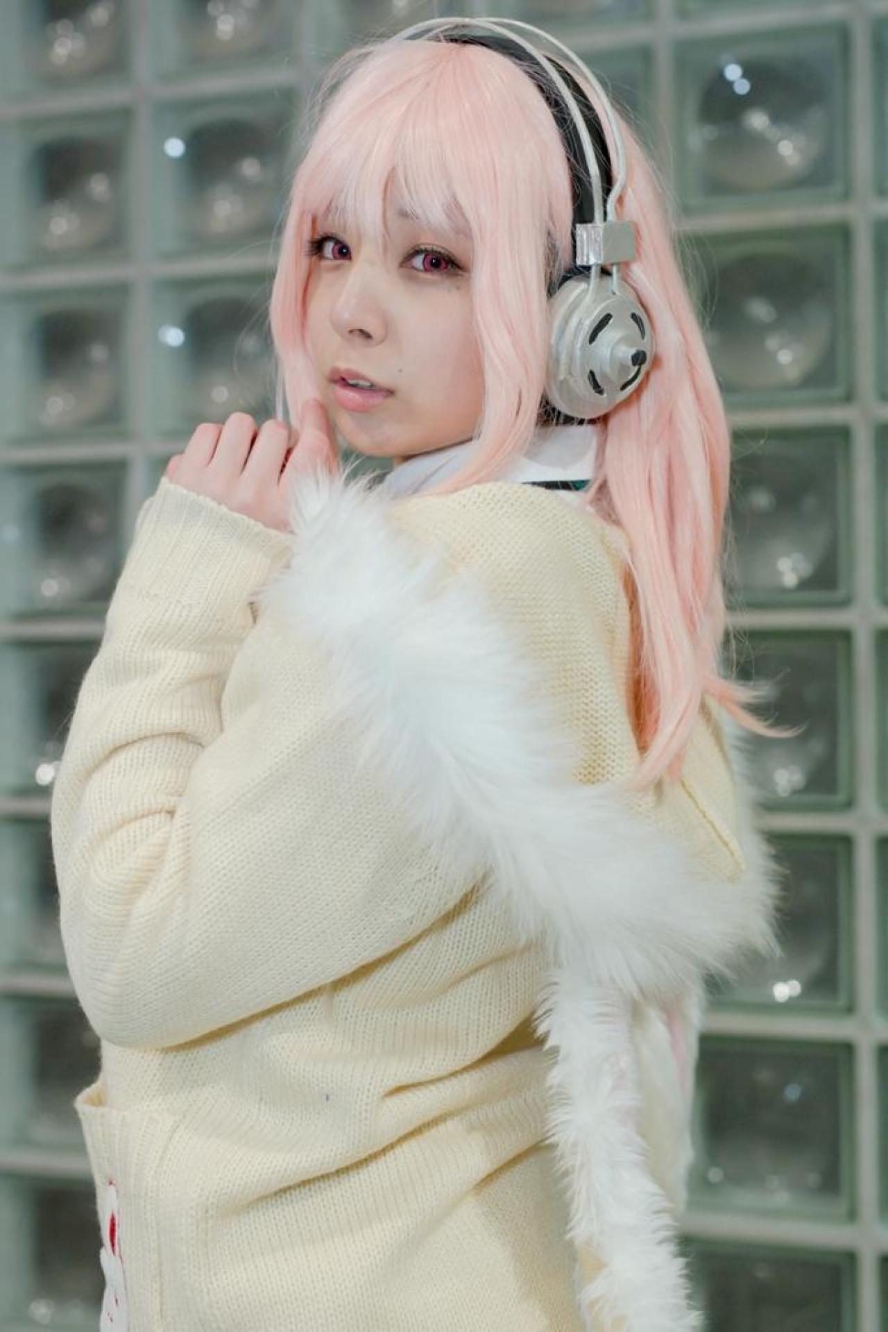 です扮超级索尼子戴着耳机，双手紧扣贴在下巴，侧身回眸