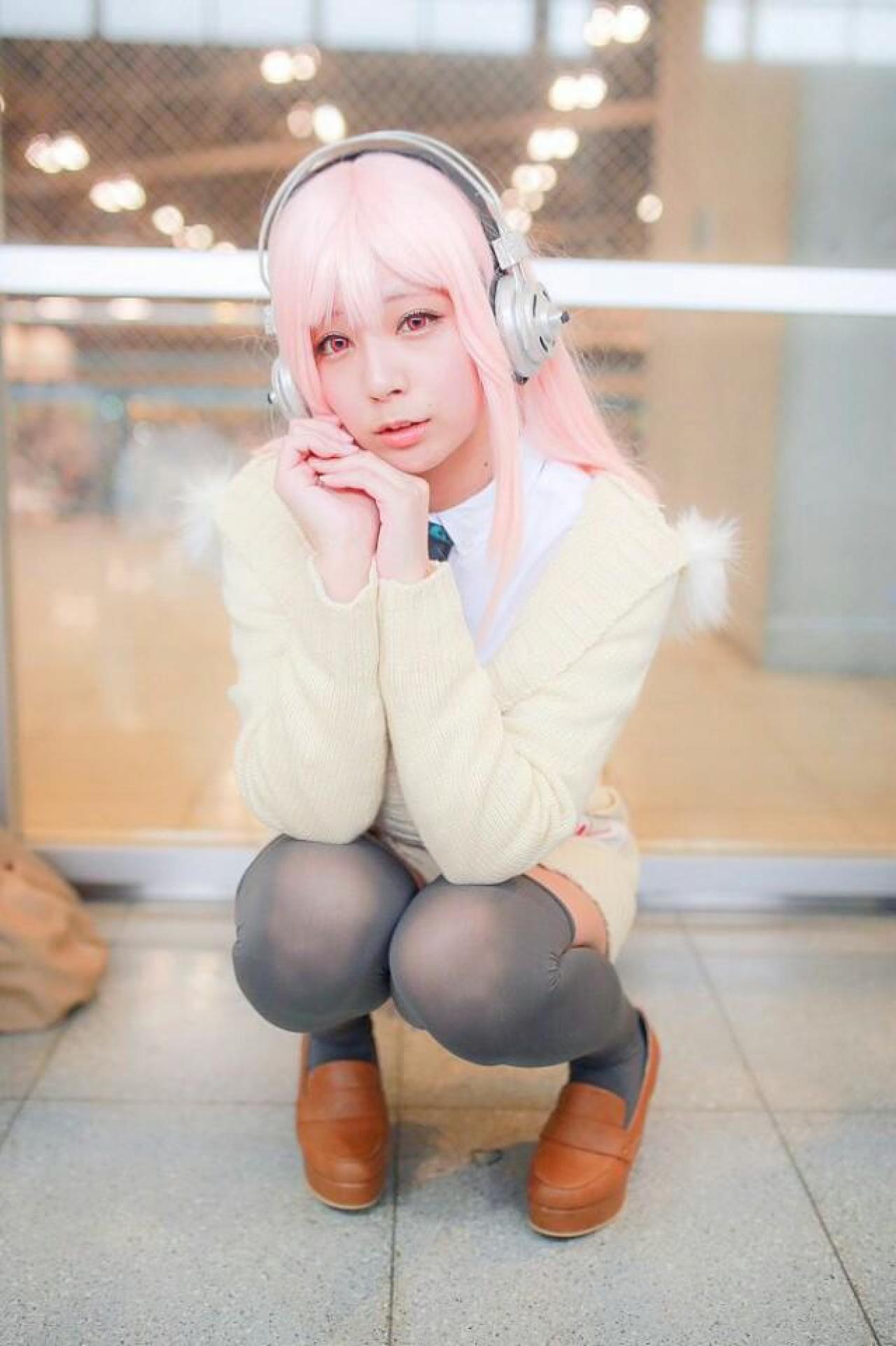 です扮超级索尼子歪着头，双手扣在一起，贴着脸颊，蹲姿