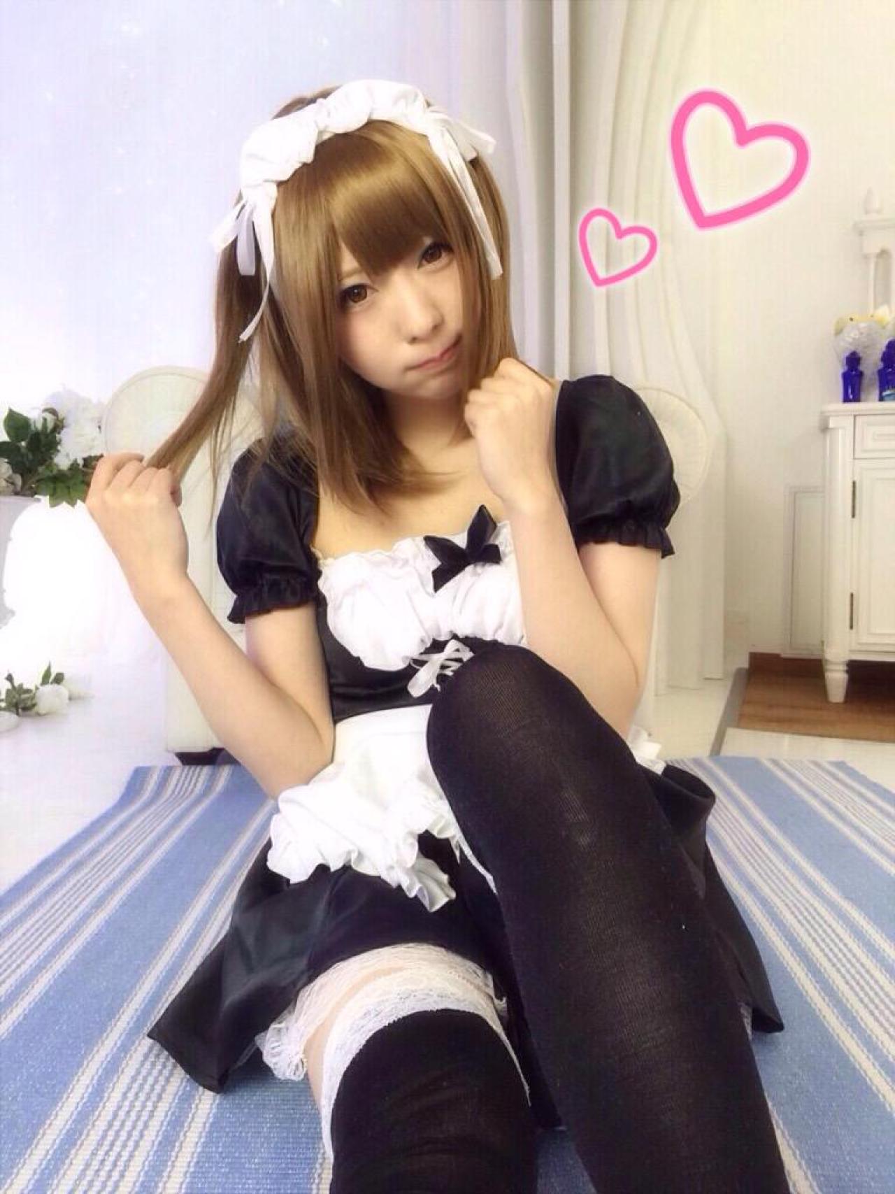 まゆふぁむ抿嘴坐在地毯上，抬起双臂，右手捋起发梢，右上角画着心形图案