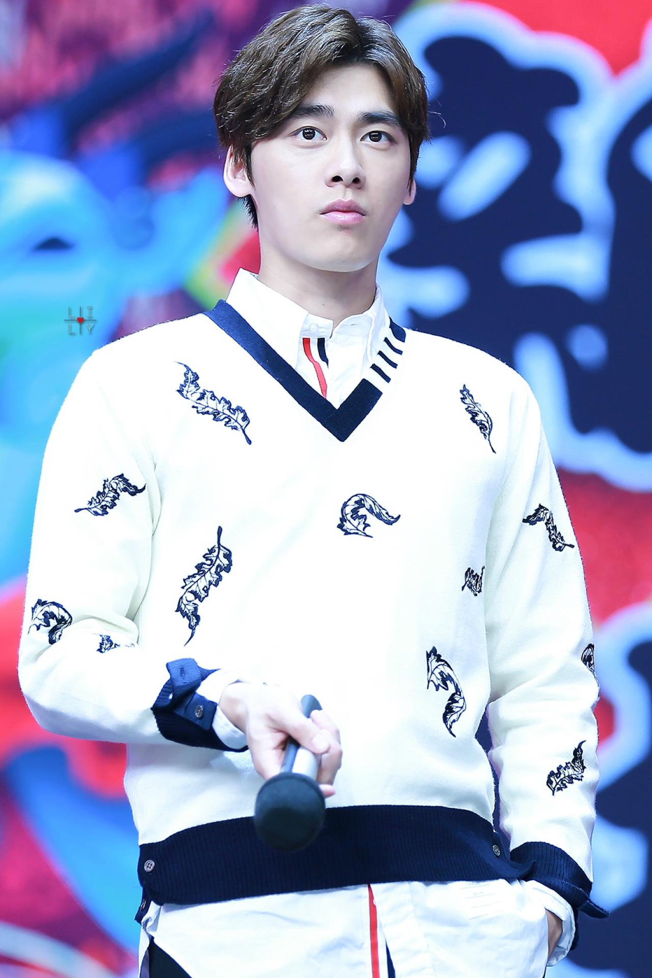 李易峰左手插兜，右手拿着话筒，平静的表情