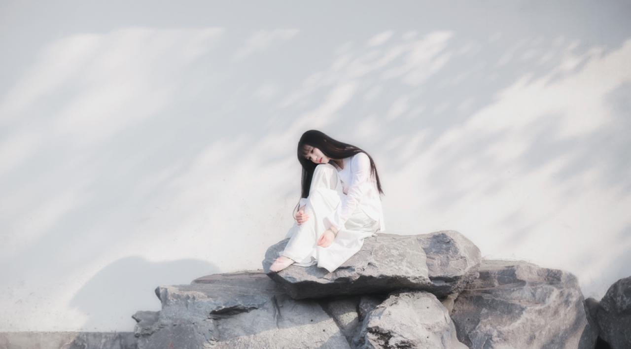 七七坐在石头上，头贴在膝盖上