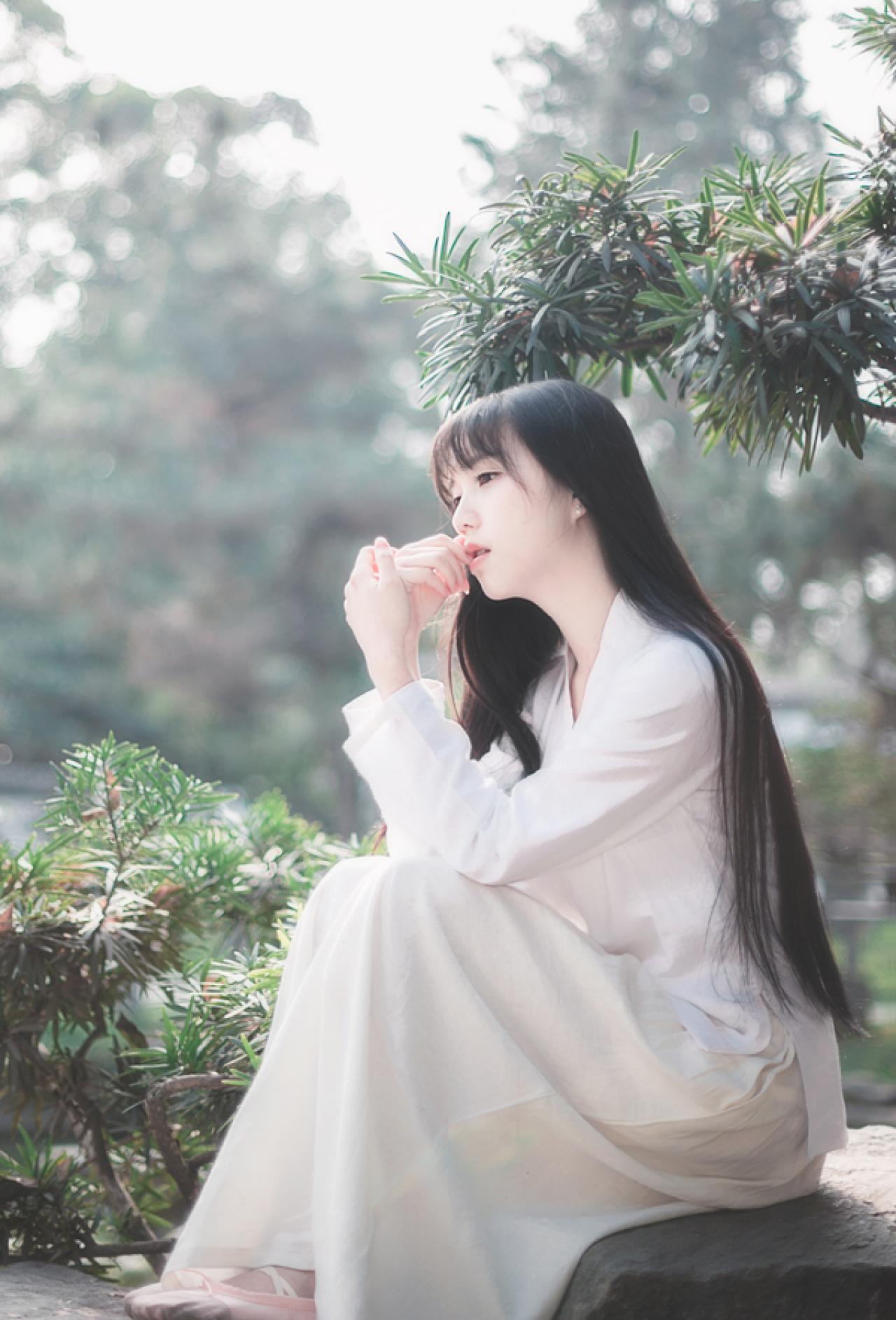 七七侧身坐在石头上