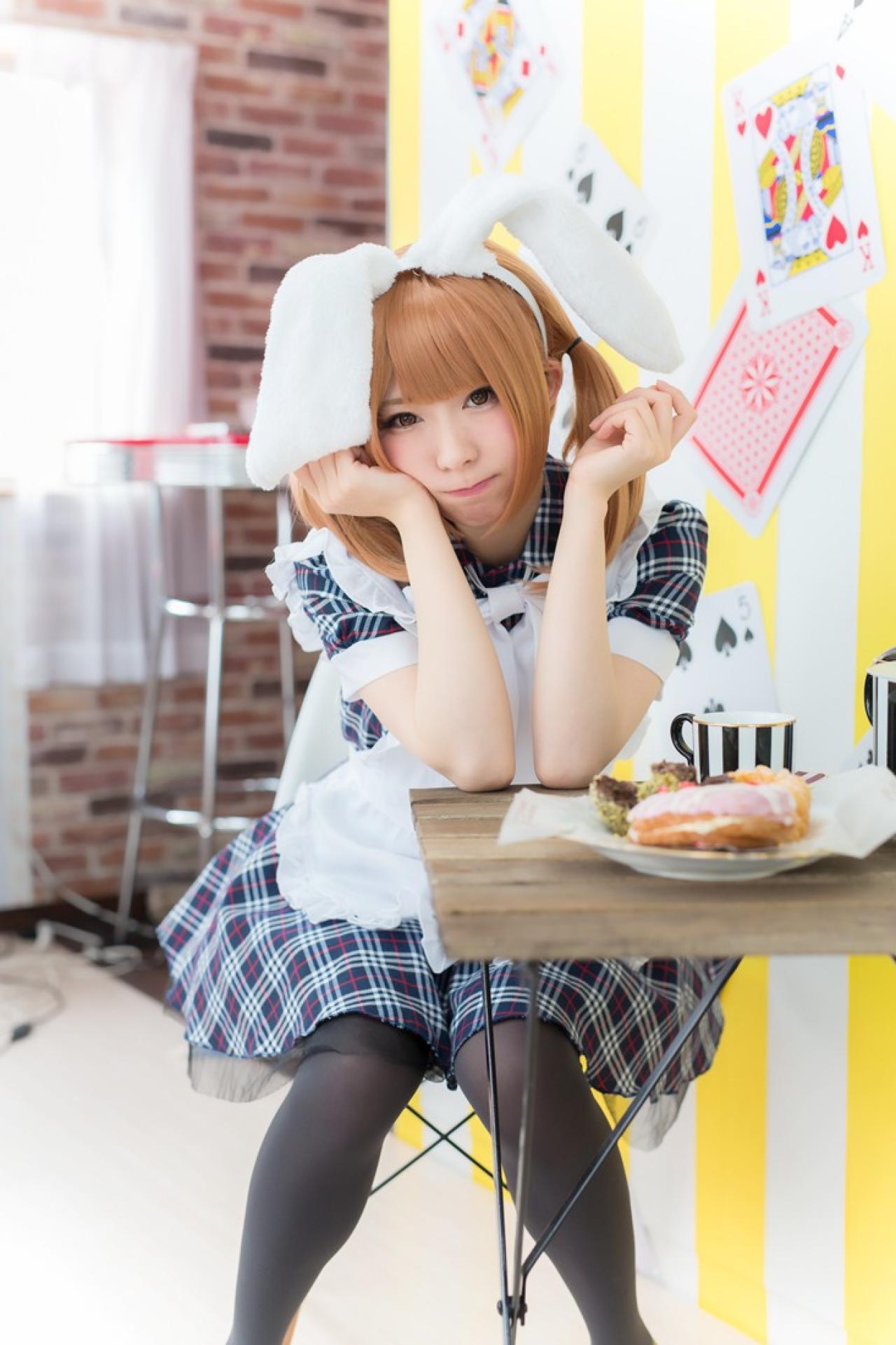 まゆふぁむ坐在椅子上，双臂撑在桌子上，歪着头，抿嘴卖萌