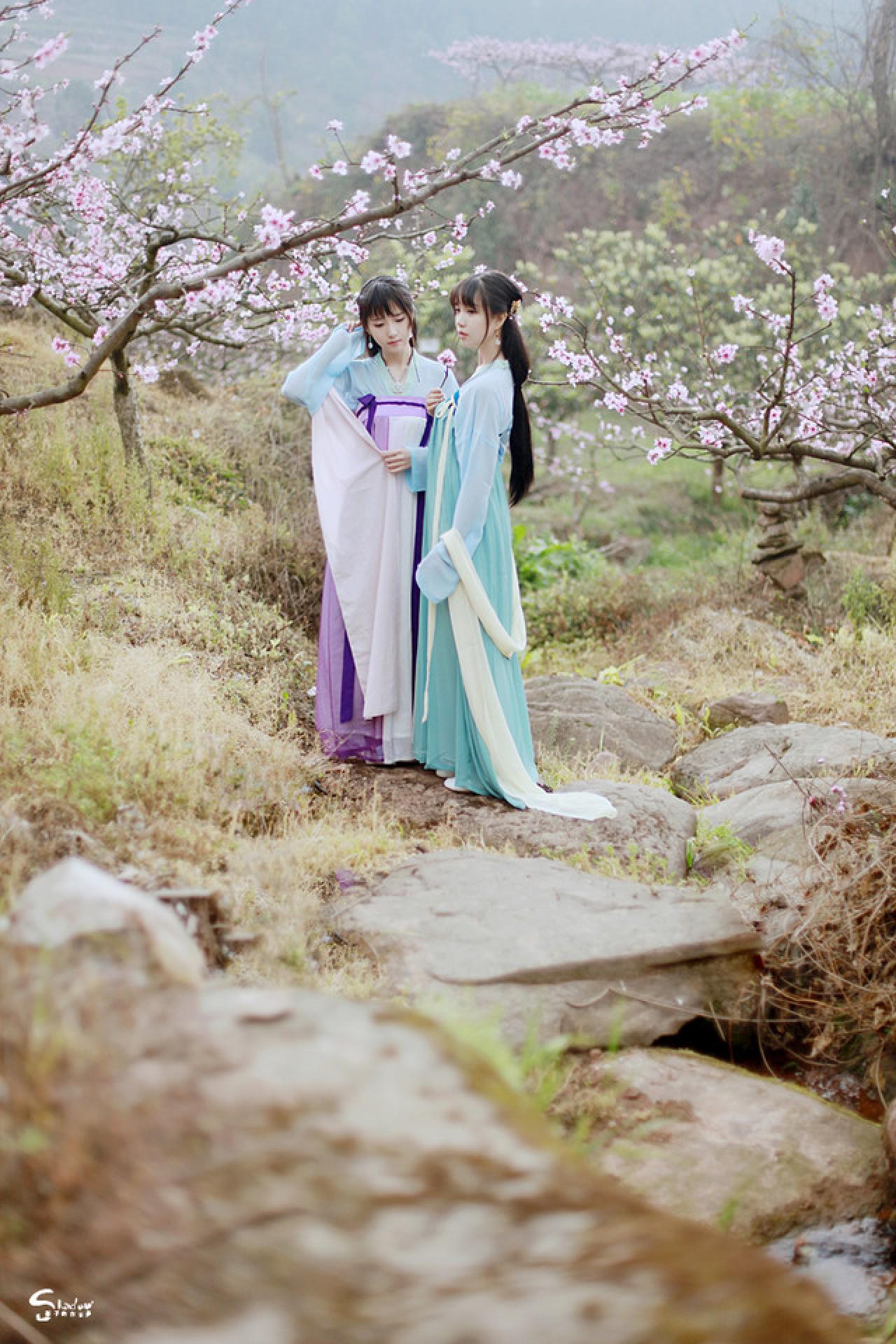 加加代撑起丝带，轻扶发簪，七七手持桃花侧面站立